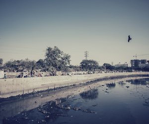 People sitting by the side of a dirty nullah