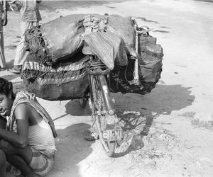 Coal carrier sitting beside his cycle with coal on it