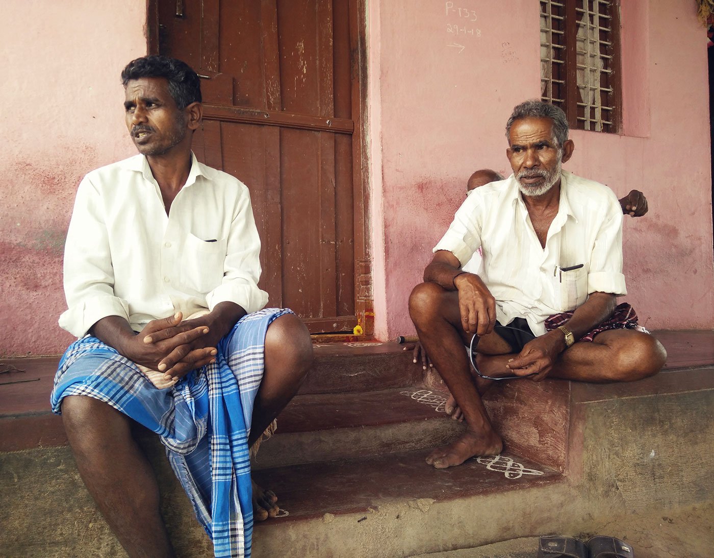 Two men sitting in the front of a home