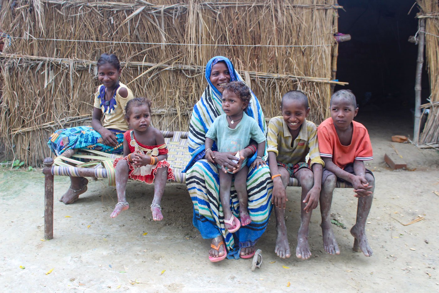 Sudama Adivasi and her children, on a cot outside their hut in Aneai village. 'We have seen times when our community was not supposed to have such cots in our huts. They were meant for the upper castes only,' says Sudama