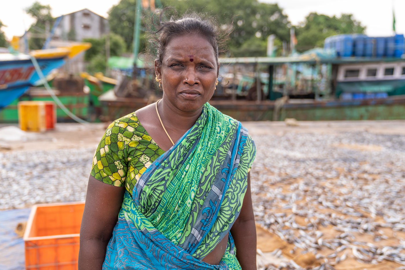 Visalatchi stands near the fish she has laid out to dry in the sun. Drying fish is the oldest form of fish processing and includes a range of activities such as salting, smoking, pickling and more