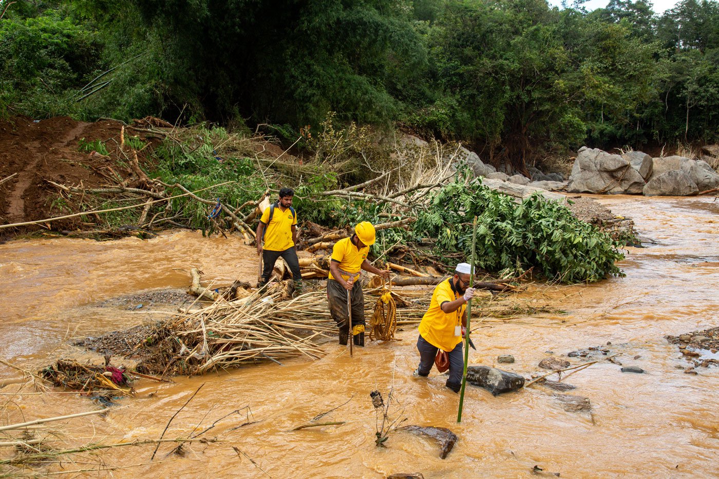 Volunteers use sticks to prevent sinking into the wet soil as they walk