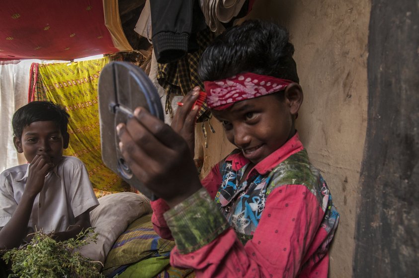 A boy applies makeup to his face