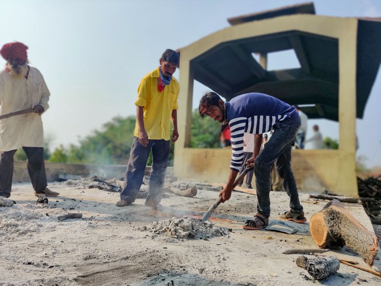 Ganesh (in blue and white t-shirt) gathers the ashes after cremation of bodies. He helps Rama Gandewad, his father-in-law, in the cremation work