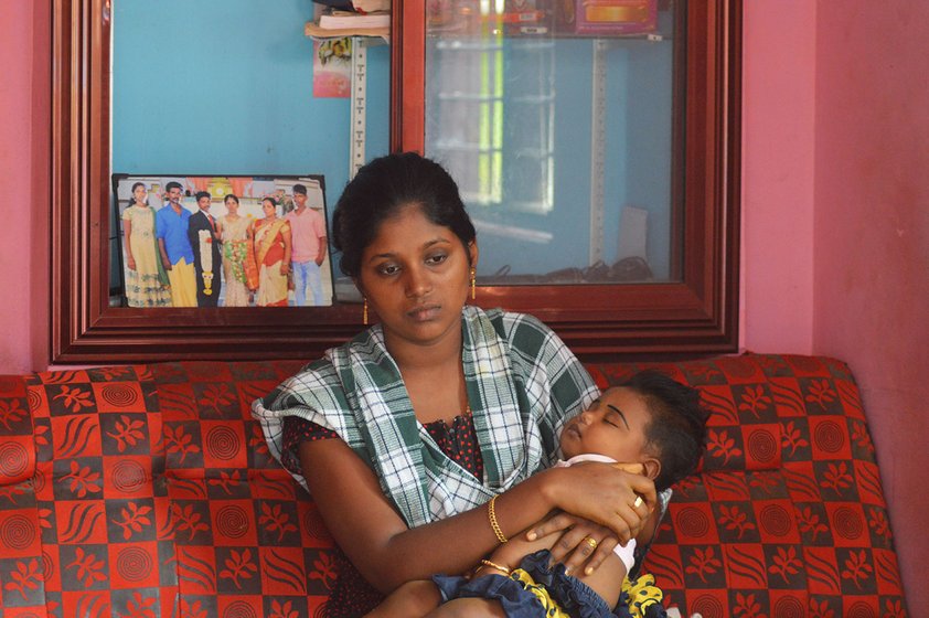 Woman sitting on sofa holding her sleeping child