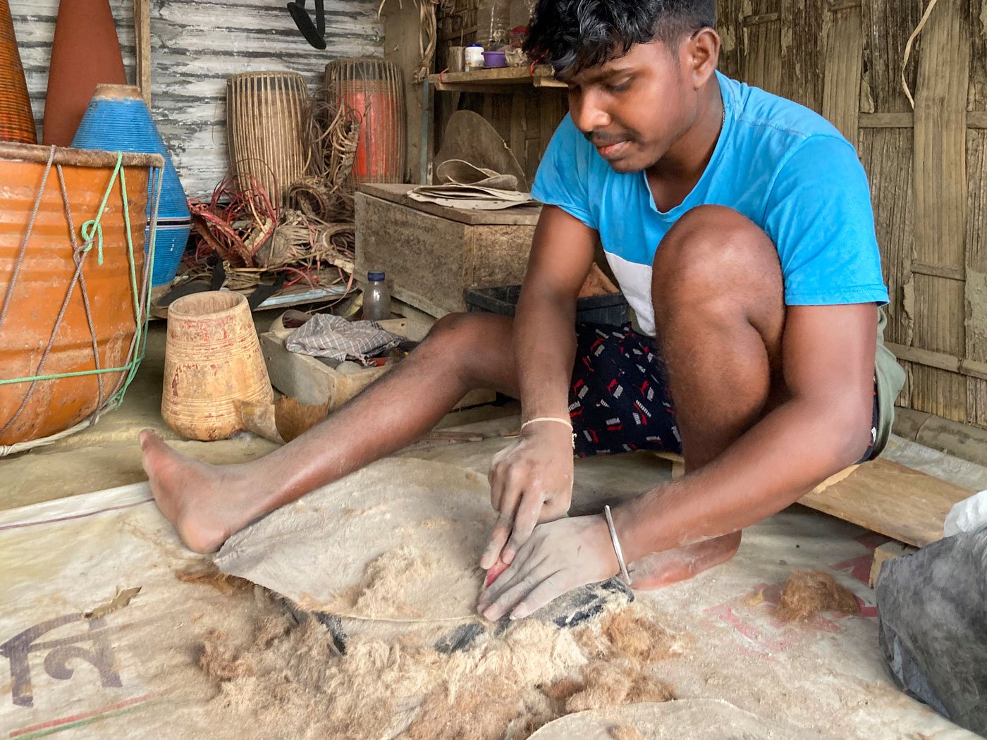 Podum scrapes off the matted hair from an animal hide using some ash and a flat-edged chisel