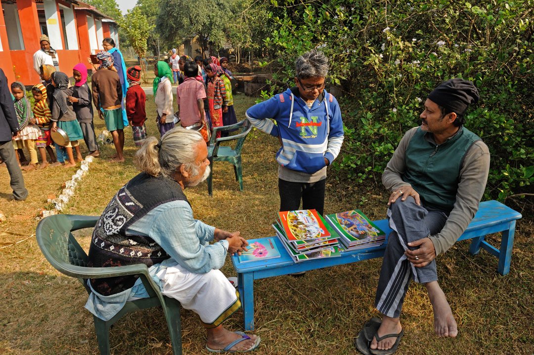 Reba Murmu, with the short hair, thinking about how to assess the drawing abilities of her students, who stand in queue in the background to collect breakfast