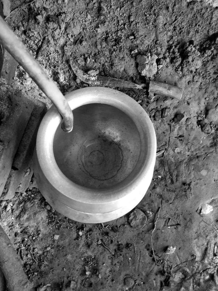 The metal utensil connected to the pipe collects the dripping condensation. The distillation process is time-consuming