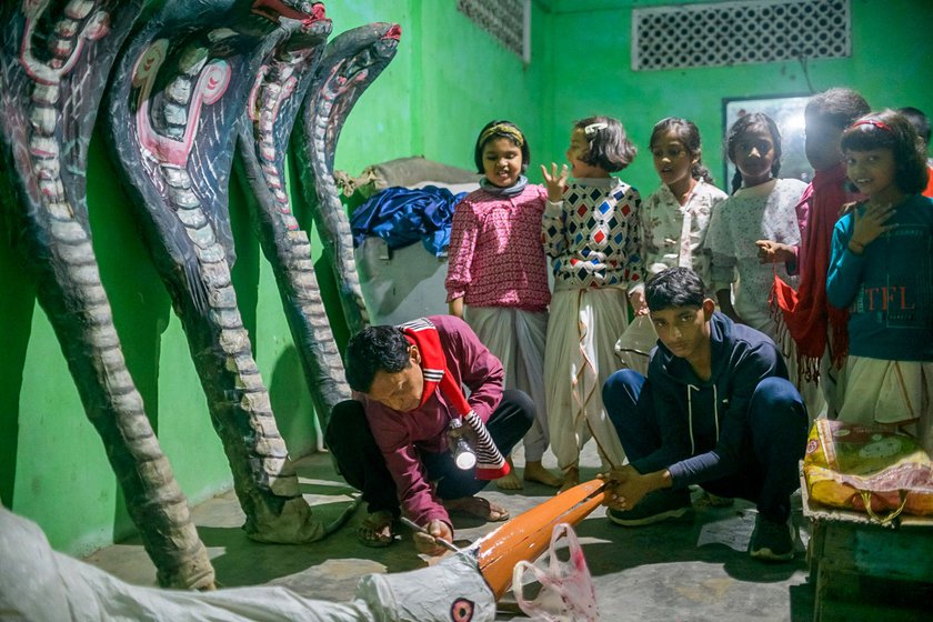 Right: Curious children look on as he applies finishing touches to a crane costume to be used during Raas