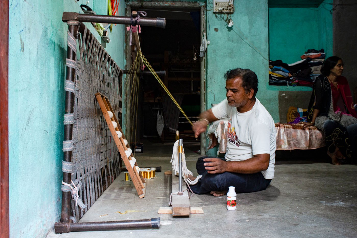 Gautam Bhai Vaghela of Mota Timbla stretches the yarn threads from the bobbins on the big wooden frame with pegs known as aada as a way to prepare the paati (the cluster of threads) for the next step