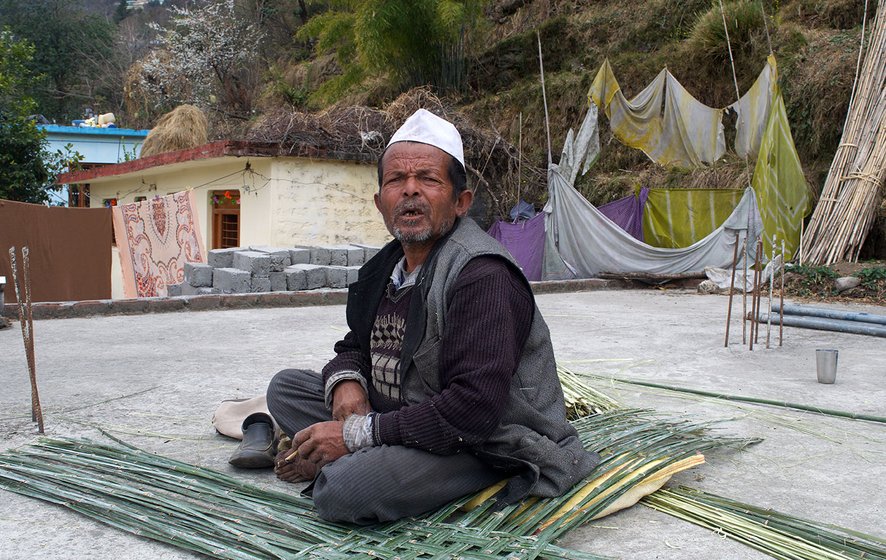 A man sitting on top of the terrace of his house amidst bamboo strips