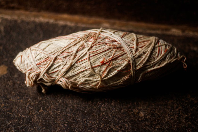 Siddu uses cotton thread to make the jali . He wraps around 20 feet of thread around the wooden takli , which he rotates against his leg to effectively roll and thicken the thread. The repeated friction is abrasive and inflames the skin