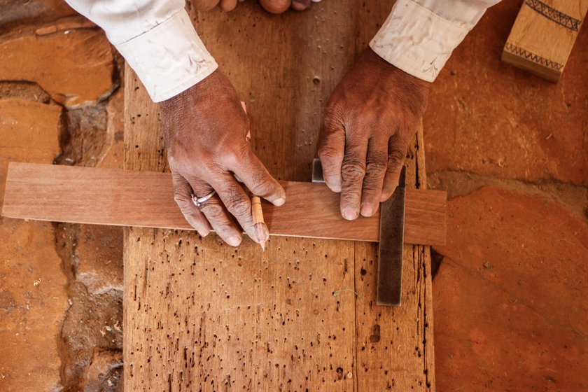 Anoparam marks out the dimensions (left) of the khartal: 7.25 inches long and 2.25 inches wide. Then, using a saw, he cuts the wood (right) into four parts