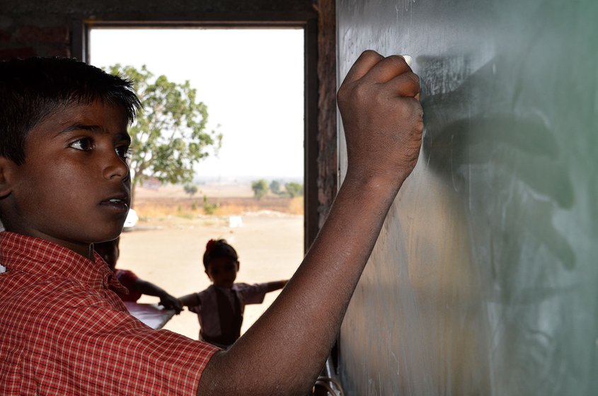 Young student writing on blackboard