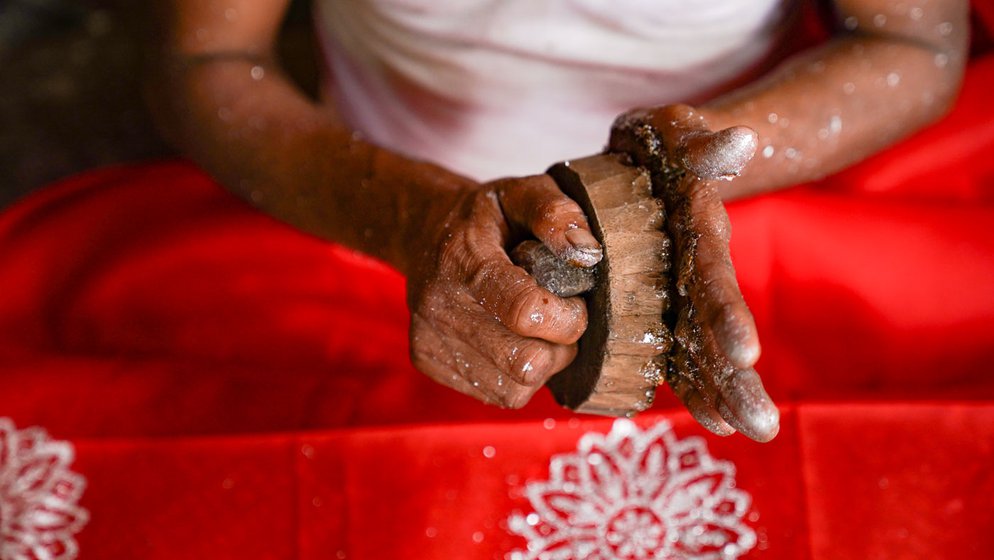 Right: He rotates the wooden flower mould on his palm to soak up the glue