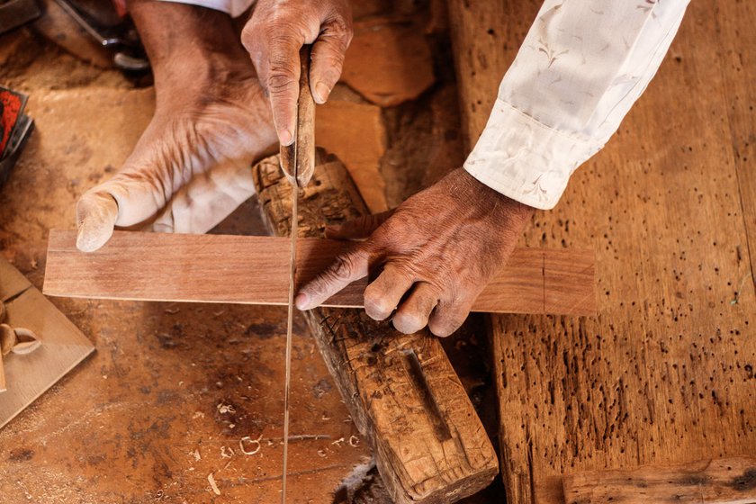 Anoparam marks out the dimensions (left) of the khartal: 7.25 inches long and 2.25 inches wide. Then, using a saw, he cuts the wood (right) into four parts