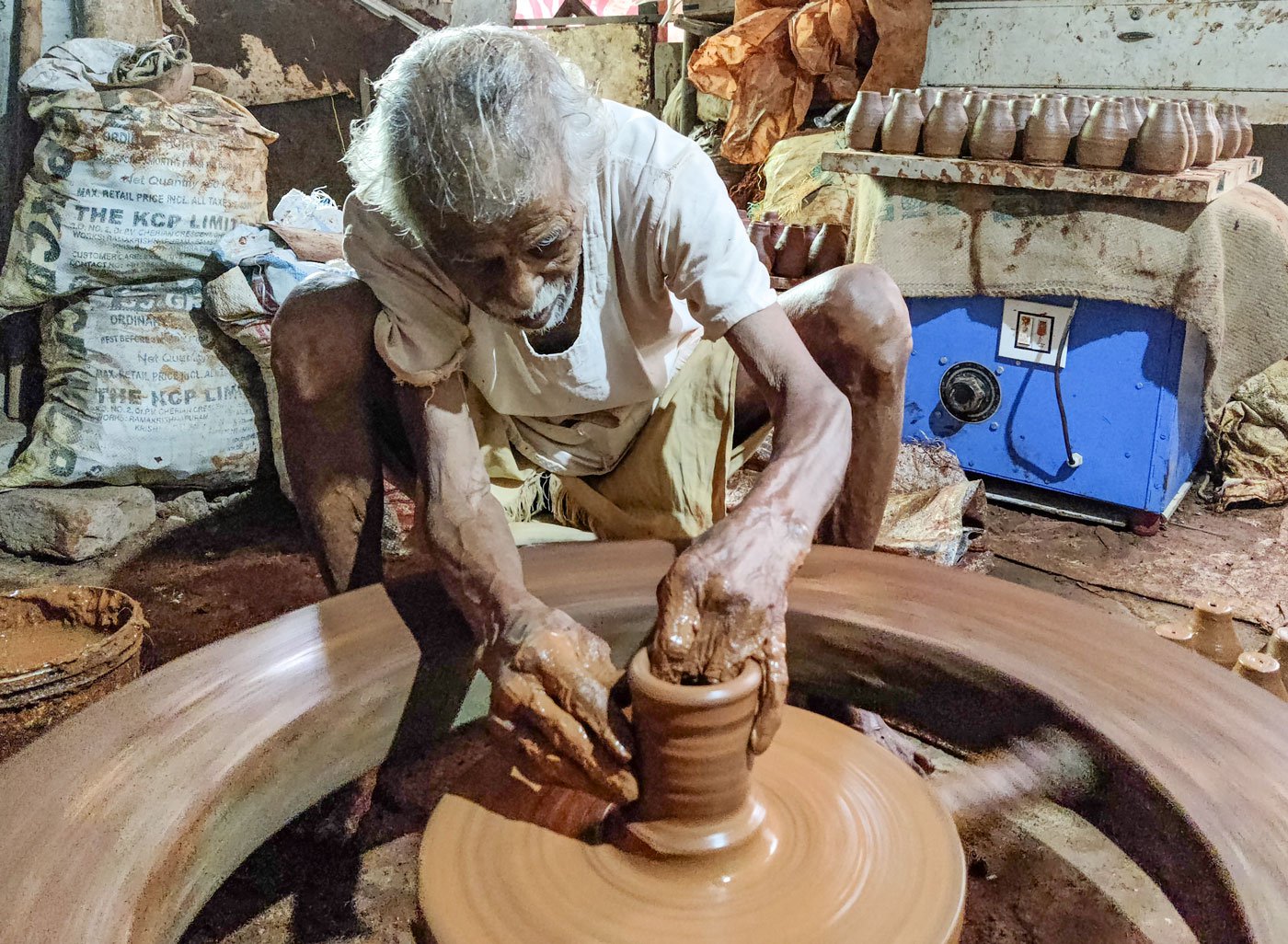 On a rainy day, Paradesam moves to a makeshift room behind his home and continues spinning out diyas