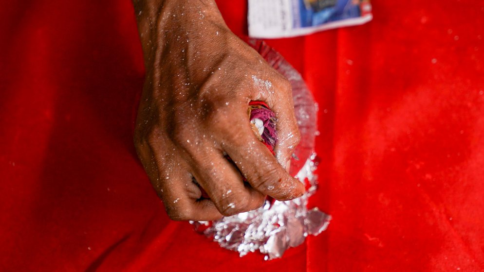 Left: Asghar stamps the sticky mould onto the cloth. Then he carefully pastes the foil sheet on the stamped part and further presses down with a pad until it is completely stuck.