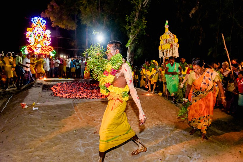 He then leads the fire walkers (right) as they go around the bed of embers