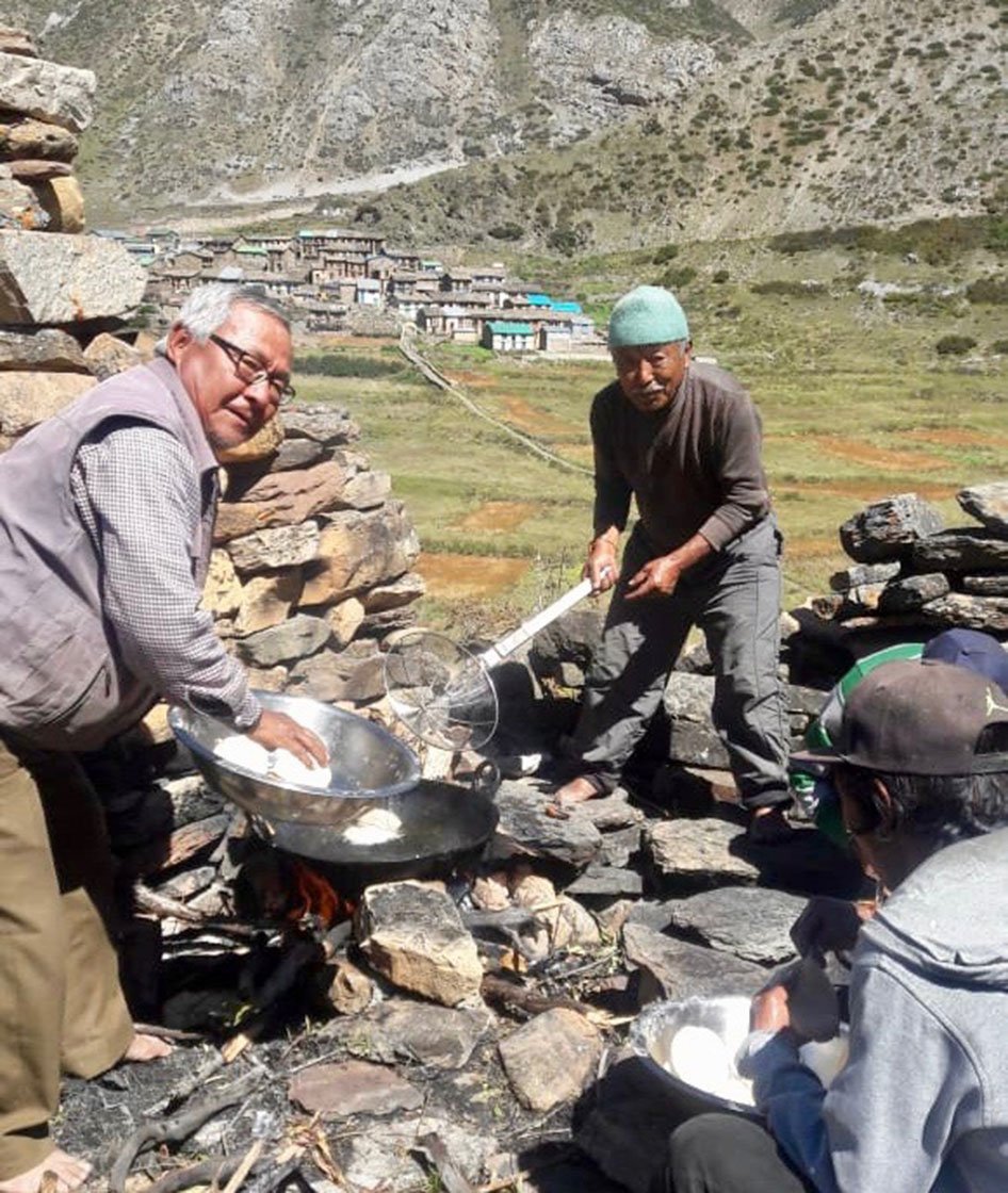 Kutiyal and other villagers are cooking. Behind, their village Kuti stands tall