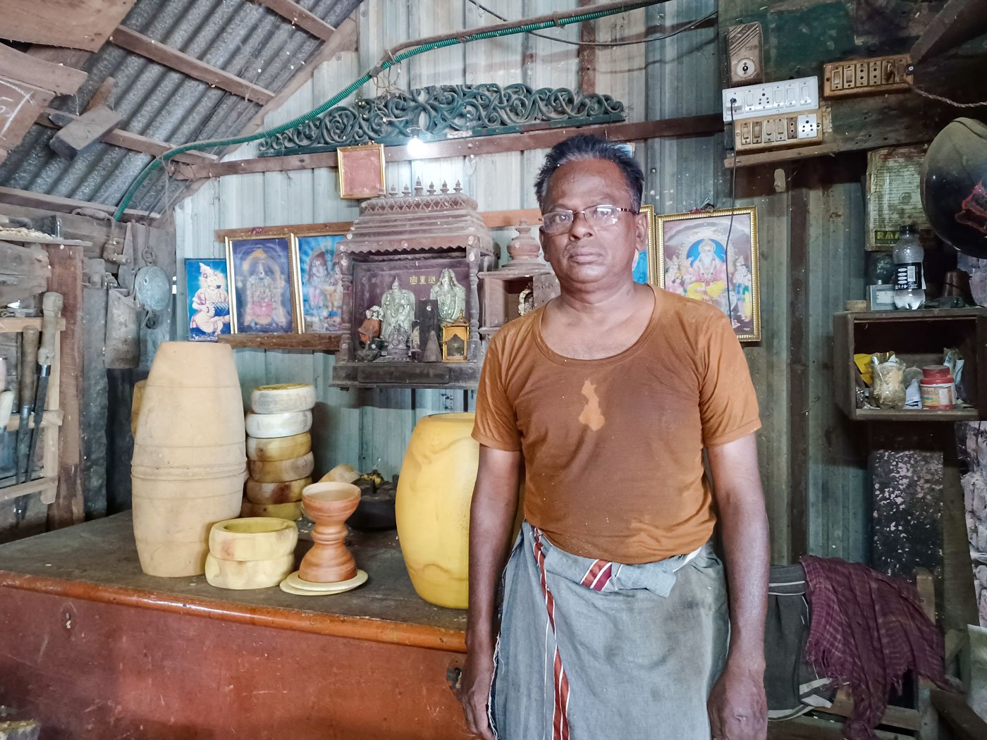 Kuppusami Asari in his workshop in Panruti town, standing next to the musical instruments made by him