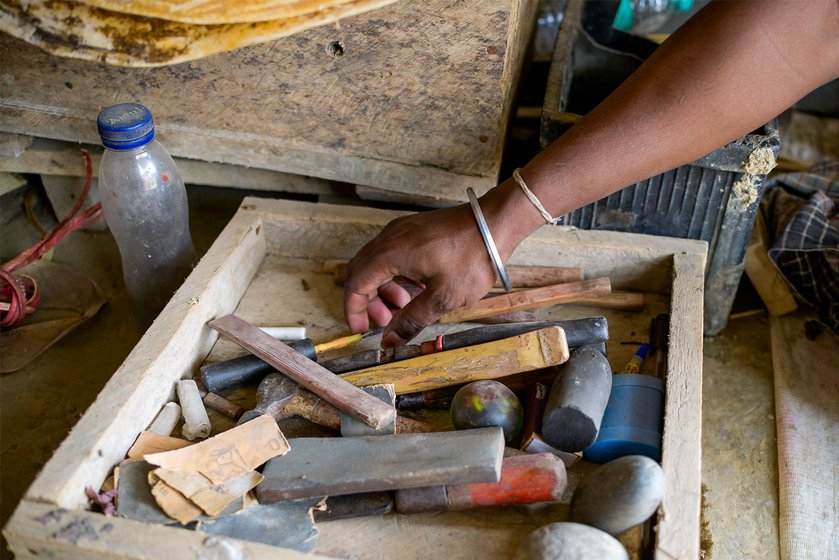 Giripod and Podum cut small sheets from the hide to fit the instruments being worked on. A toolbox holds the many items necessary for preparing the leather: different types of chisels, blades, a hammer, mallet, stones and sandpaper