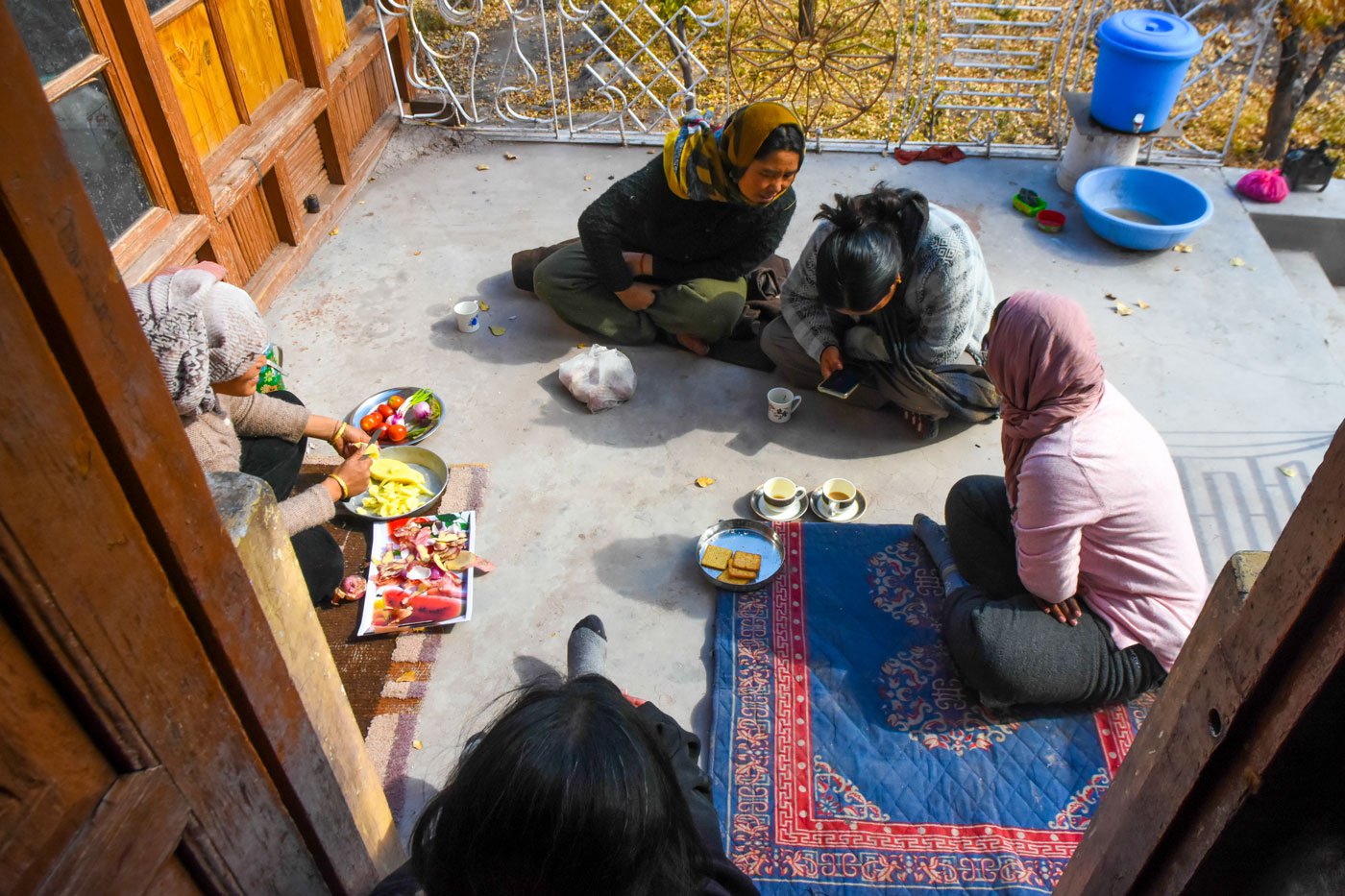 During a tea break, Urgain Chodol and Tsering Spaldon are joined by visitors interested in Thangka restoration work, while Thinles Angmo prepares lunch with vegetables from her farm.