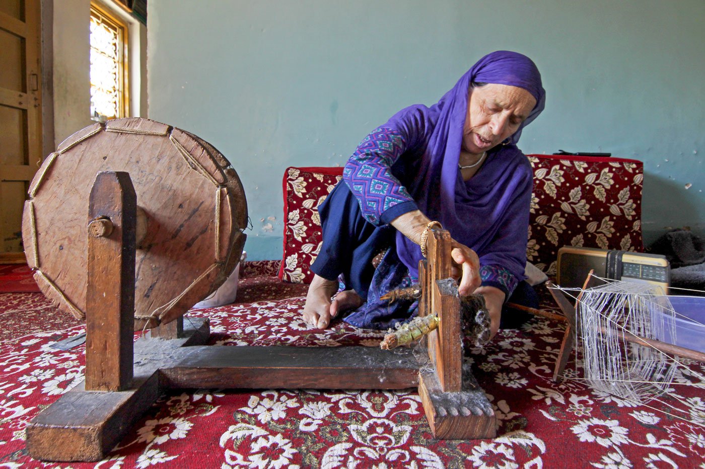 Khatija getting the spinning wheel ready to combine the threads