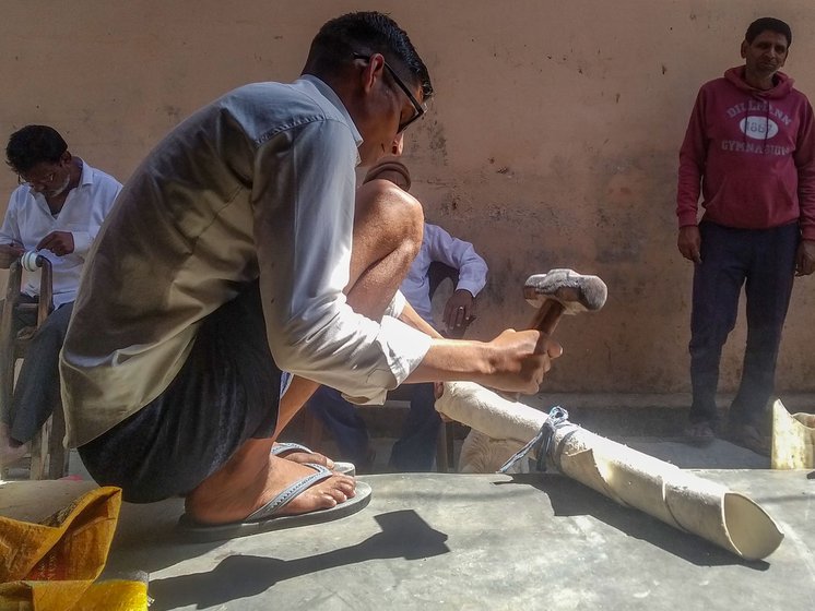 Sunil (left) beats a roll of processed leather with a hammer to make it pliable, a step locals call melli maarna