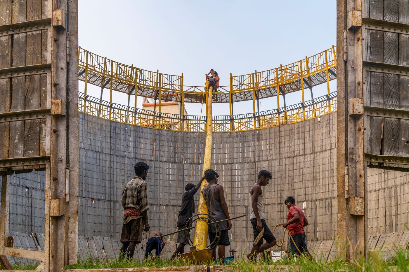 A group of people haul up the pole on which the tent cover rests after the structure is complete