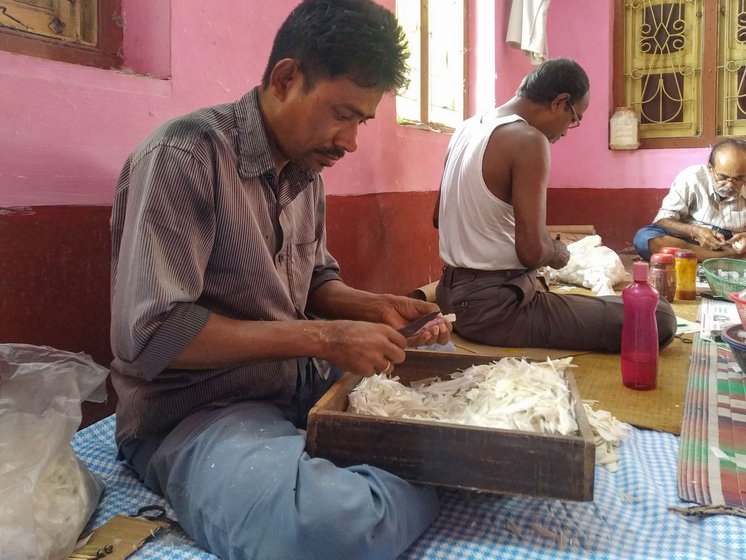 Montu Partha (left) along with Bhabani Adhikari and Likhan Majhi (right) shape the trimmed feathers