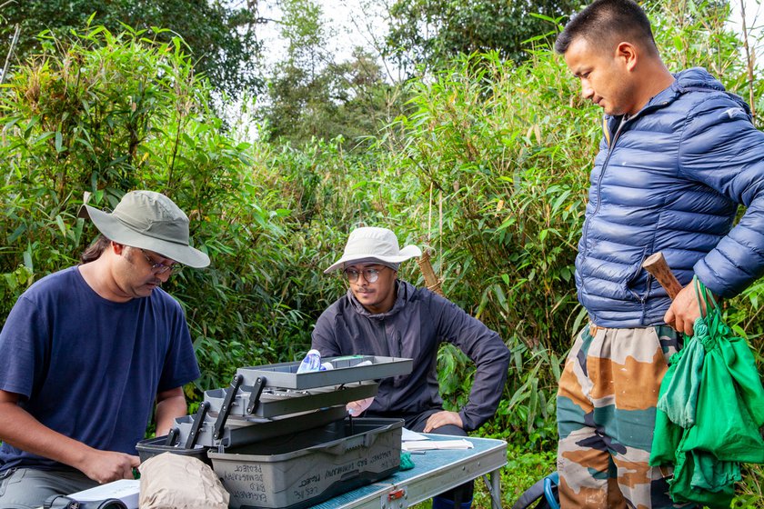 Left: Srinivasan (left) and Kaling Dangen (right) sitting and tagging birds and noting data. Micah holds the green pouches, filled with birds he has collected from the mist netting. Micah i nspecting (right) an identification ring for the birds