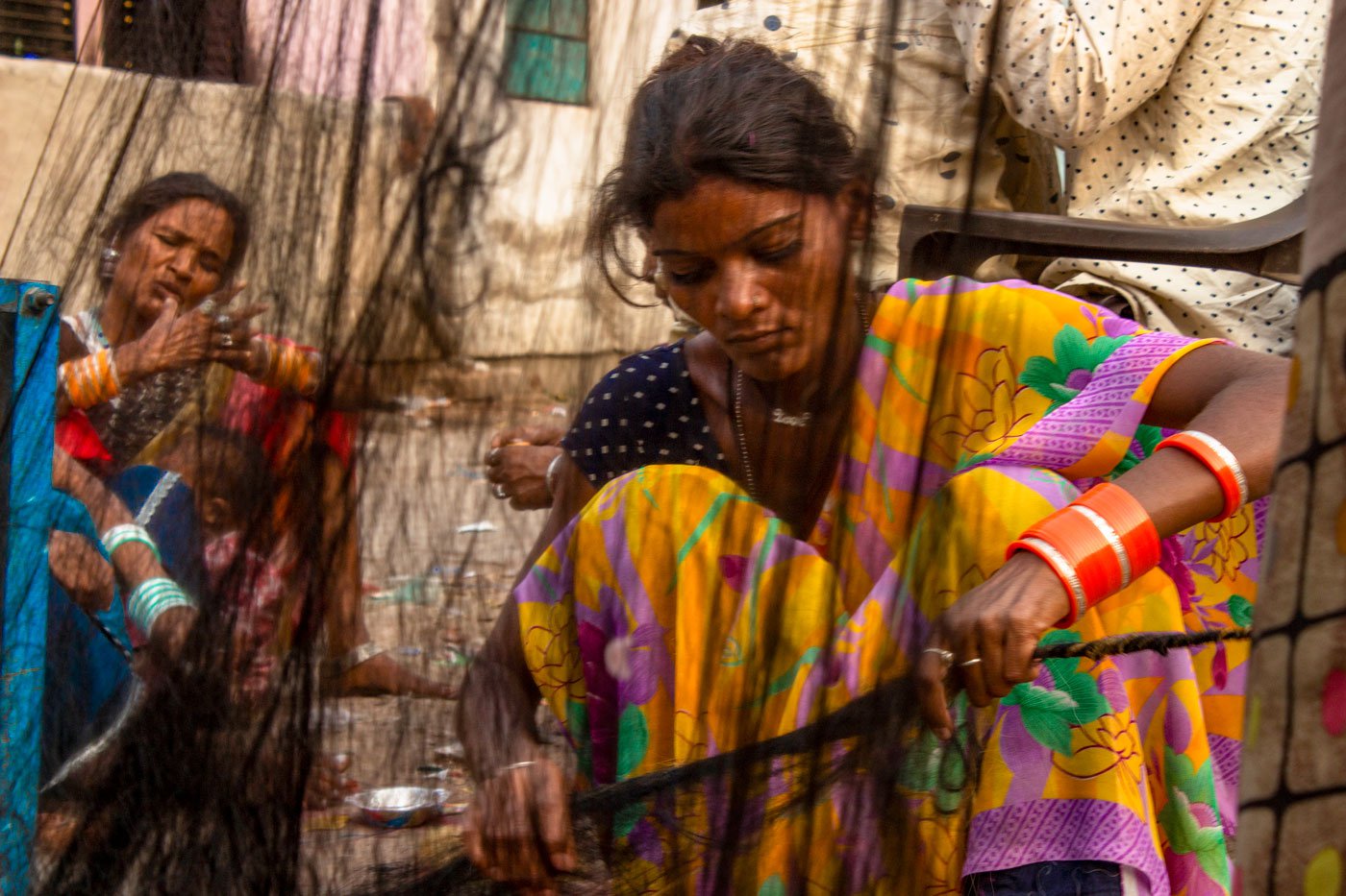 The process requires collective effort. One woman spins the wheel while another keeps the strands from getting tangled