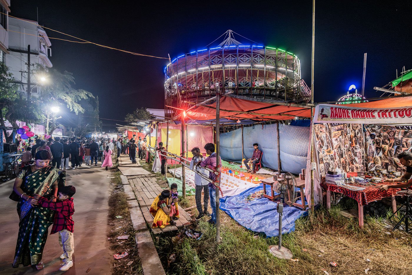 The entrance to the fair-ground is marked with multiple makeshift stalls selling different kinds of products