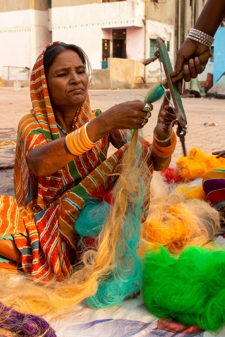 A small hand wheel and a large fixed spinning wheel are two important tools of their trade