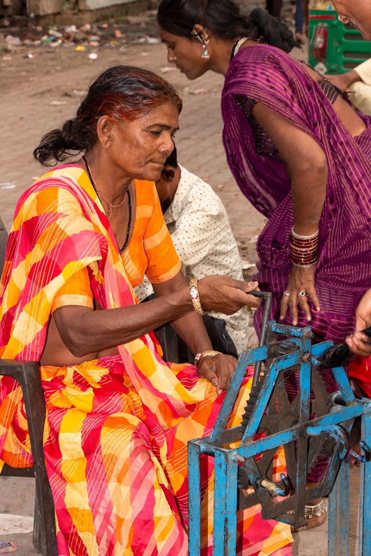 A small hand wheel and a large fixed spinning wheel are two important tools of their trade