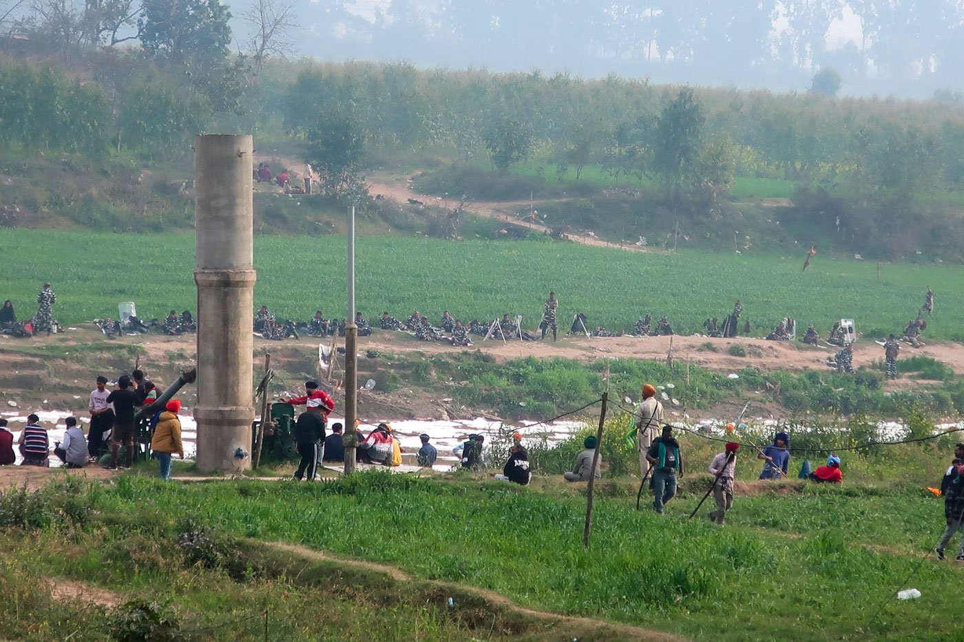 On the other side of the road, protesters and the forces sit facing each other across the Ghaggar river