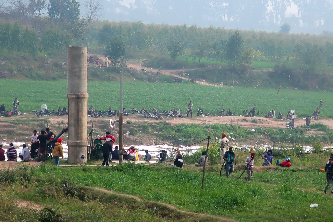 On the other side of the road, protesters and the forces sit facing each other across the Ghaggar river