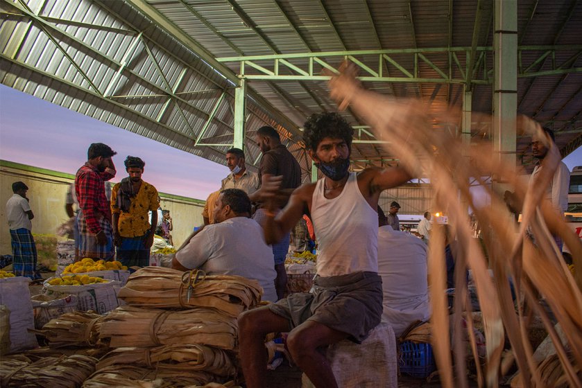 Right: A worker measures and cuts banana fibre that is used to make garlands. The thin strips are no longer used to string flowers