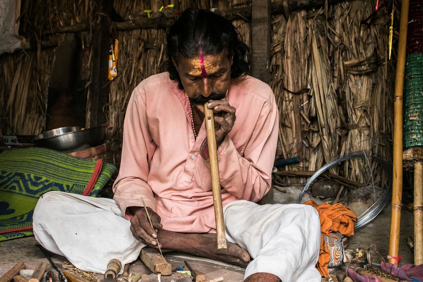 Narayan marks the tone holes (left) of a flute using the wooden reference scale he made and then checks if it is producing the right tones (right)