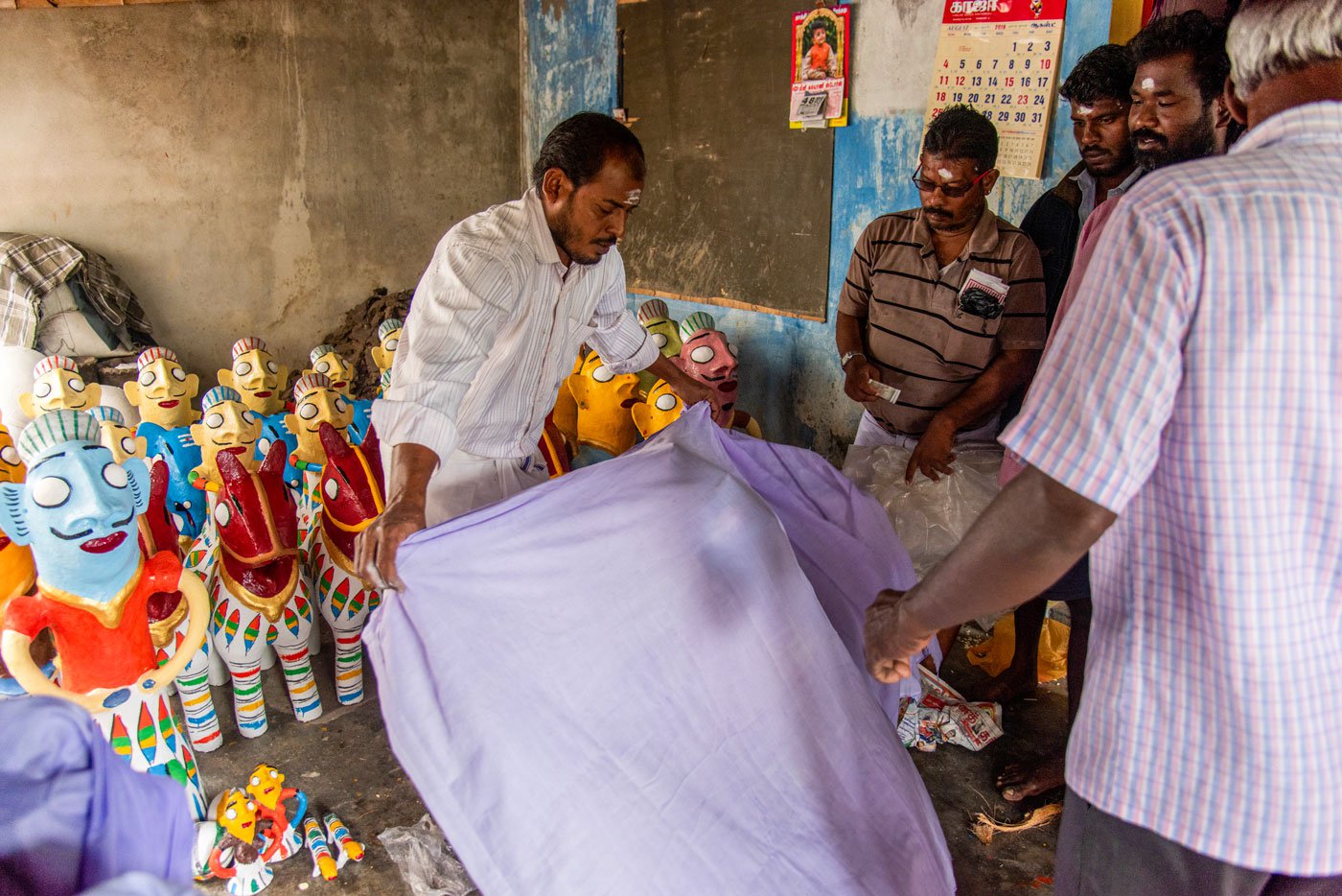 Dilli anna wrapping a white cloth around the idols prior to selling