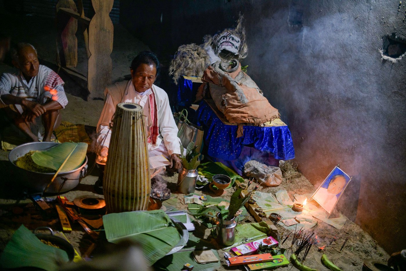 Munim Kaman (centre) lights a lamp in front of Domodar Mili's photograph at the prayers marking the beginning of the festival in Borun Chitadar Chuk. Mili, who passed away a decade ago, taught the people of the village to organise raas