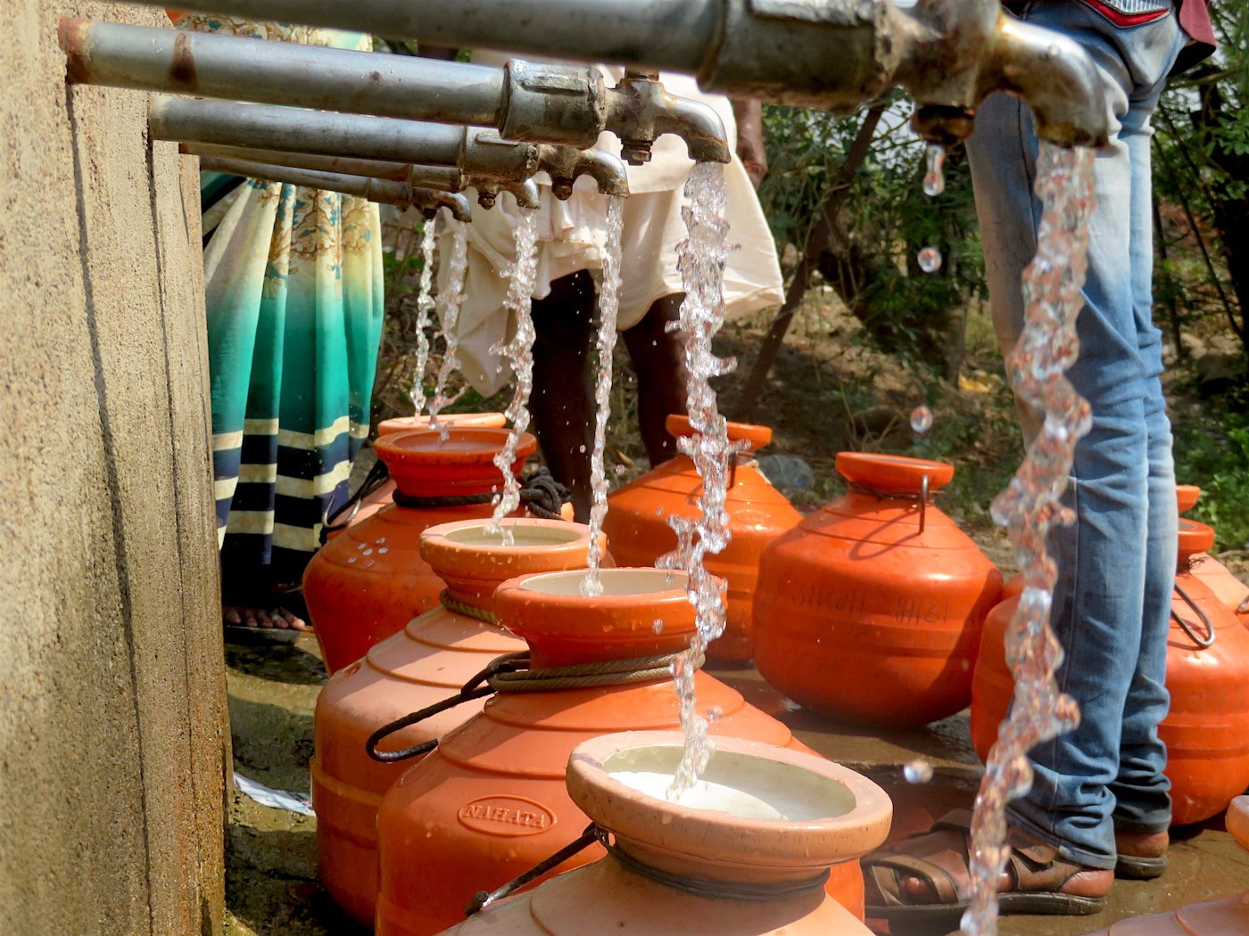 pots are filling with the water from tap