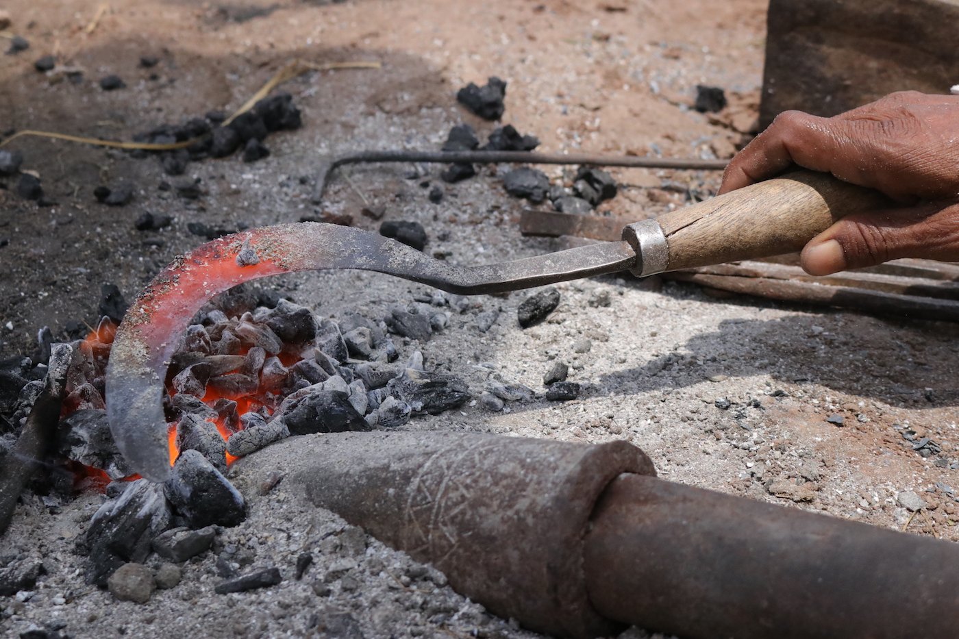 A photograph of Ramling Chavan's hand turning the sickle in the flames