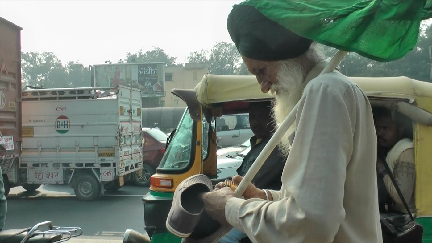 Old Sikh farmer walking on the street. Holding shows and biscuit packet