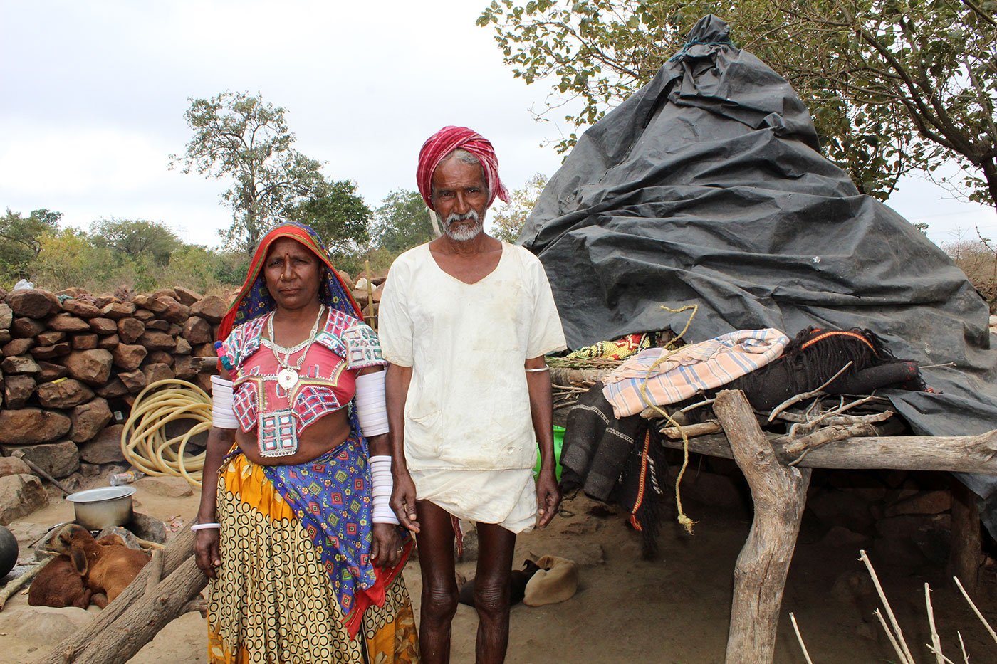 Husaband and wife stand with their cattles behind